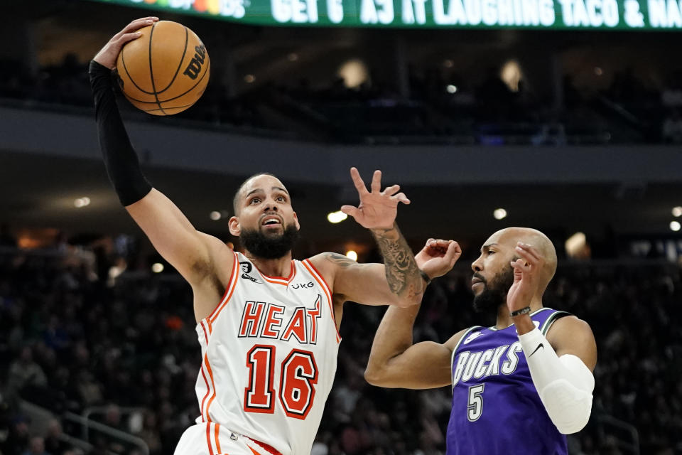 Miami Heat's Caleb Martin (16) shoots past Milwaukee Bucks' Jevon Carter (5) during the first half of an NBA basketball game Friday, Feb. 24, 2023, in Milwaukee. (AP Photo/Aaron Gash)