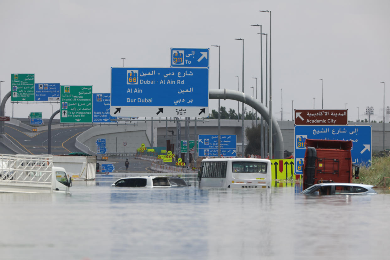 Several abandoned vehicles sit on a flooded highway after a rainstorm in Dubai, United Arab Emirates. The water reaches car windows.