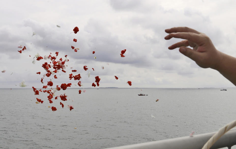 A relative throws flowers into the Java Sea where Sriwijaya Air flight SJ-182 crashed on Jan. 9 killing all of its passengers, during a memorial ceremony held on deck of Indonesian Navy Ship KRI Semarang, near Jakarta in Indonesia, Friday, Jan. 22, 2021. (AP Photo/Tatan Syuflana)