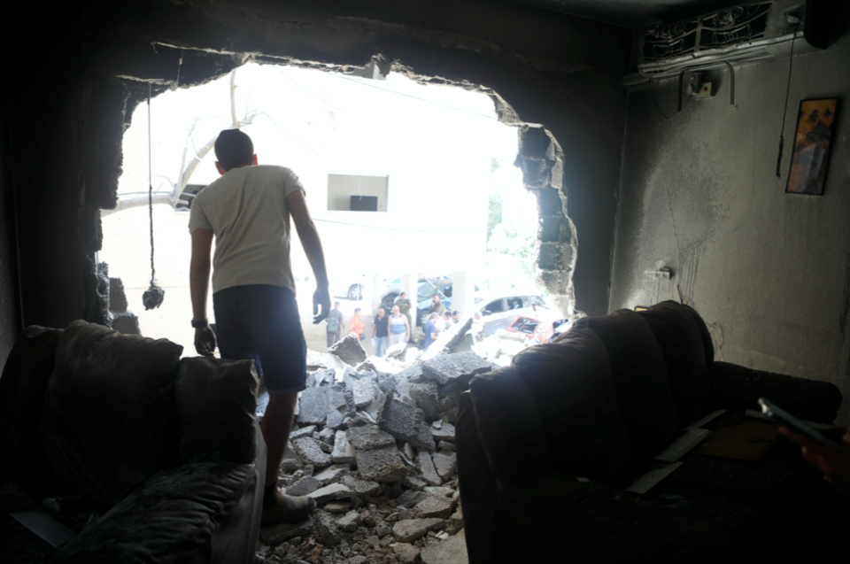 A man stands atop rubble as he surveys the damage after a rocket launched overnight from the Gaza Strip hit a residential building in Petah Tikva, Israel. (Reuters/Nir Elias)