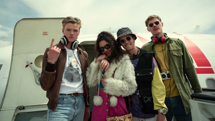 Four people pose in front of a car for a picture in White Lines.