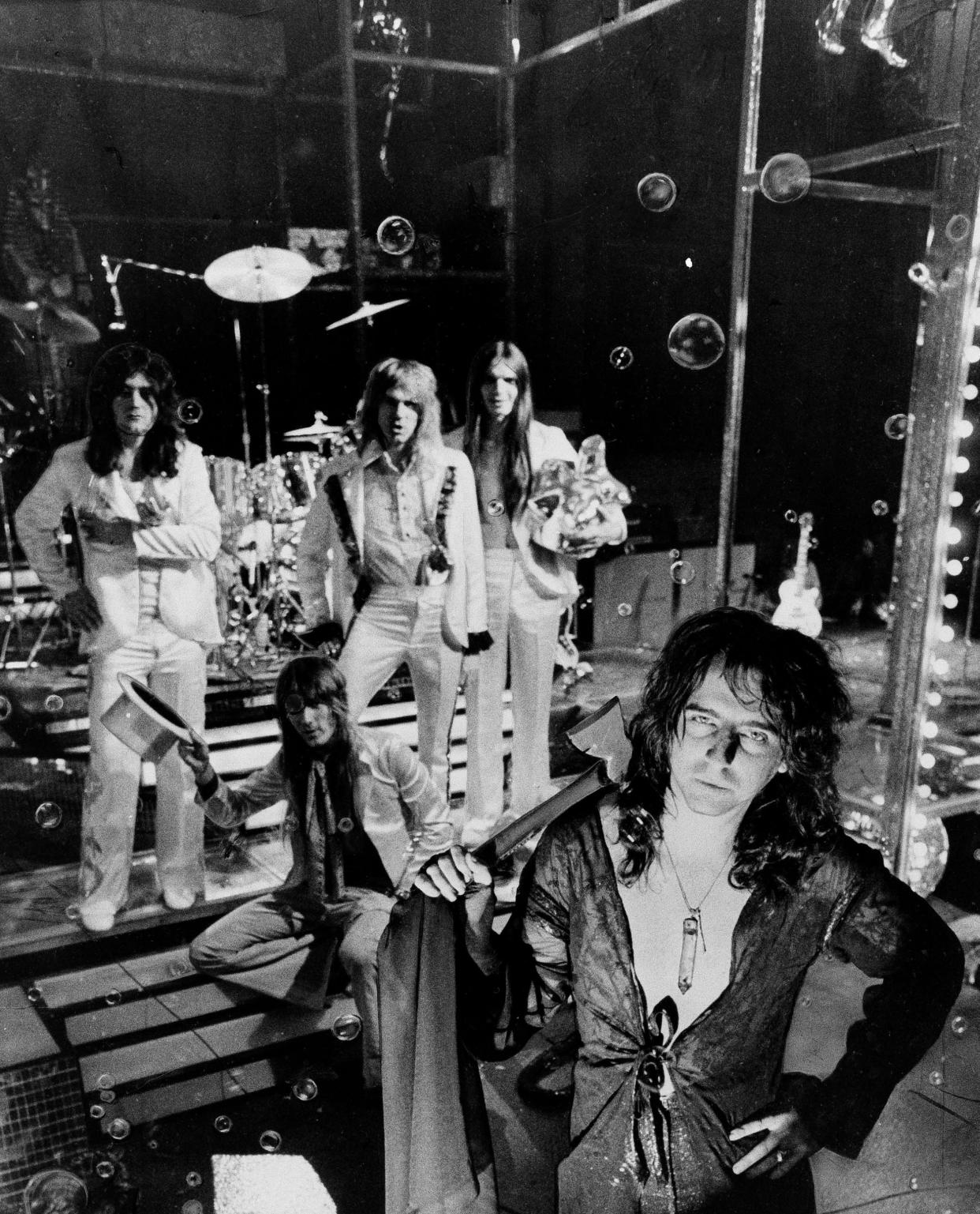 Glam rock star, Alice Cooper, foreground, with hatchet, poses with his band in New York, June 3, 1973. "It's more or less the decade of the star again" says Cooper. "The old publicity stunts work." Such stunts include: fake hangings; decapitations; a seven-foot toothbrush; a bubble machine and a male lead singer with a female's name. The band members are, left to right: Michael Bruce; Neal Smith, sitting; Glen Buxton and Dennis Dunaway. (AP Photo/Ron Frehm)