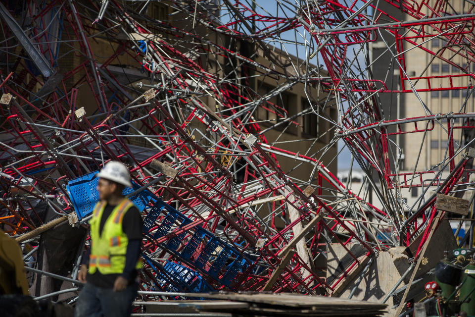 Construction workers begin cleaning up collapsed scaffolding on the 300 block of East Martin Street Friday, Sept. 20, 2019 in San Antonio. Officials say three bystanders were slightly hurt as a 100-foot (30-meter) section of scaffolding collapsed on a San Antonio street amid 50 mph (80 kph) winds from a system linked to Tropical Storm Imelda. The scaffolding, along a high-rise building, crushed several parked vehicles and crashed into St. Mark's Episcopal Church. (Daniel Carde/The San Antonio Express-News via AP)