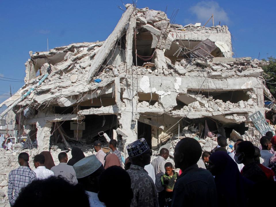 Relatives wait for bodies to be removed after a double car bomb attack at a busy junction in Mogadishu, Somalia