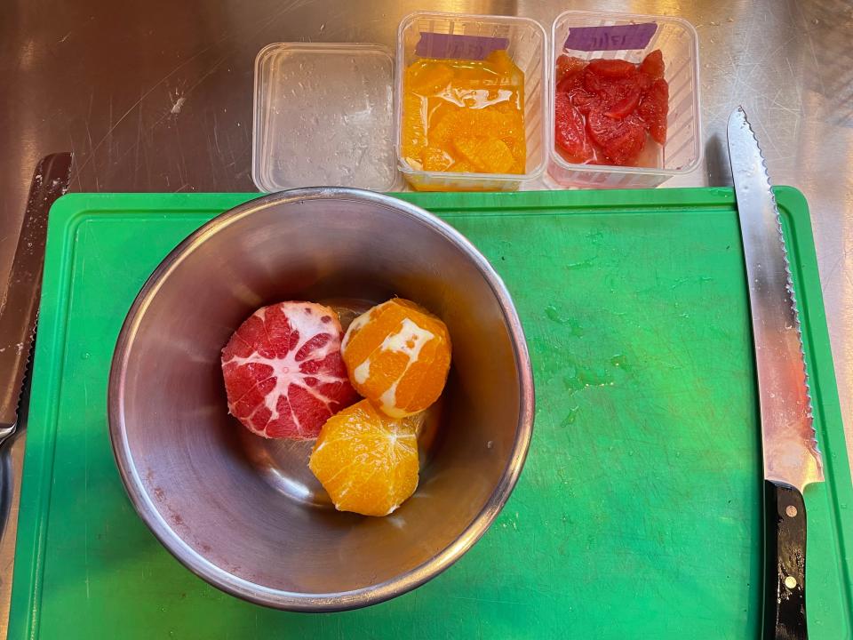 Peeled citrus in a bowl with sections in labeled bins next to bowl