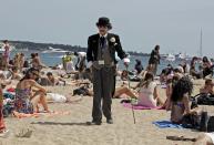 A man dressed as Charlie Chaplin walks along the beach in Cannes during the 65th Cannes Film Festival.