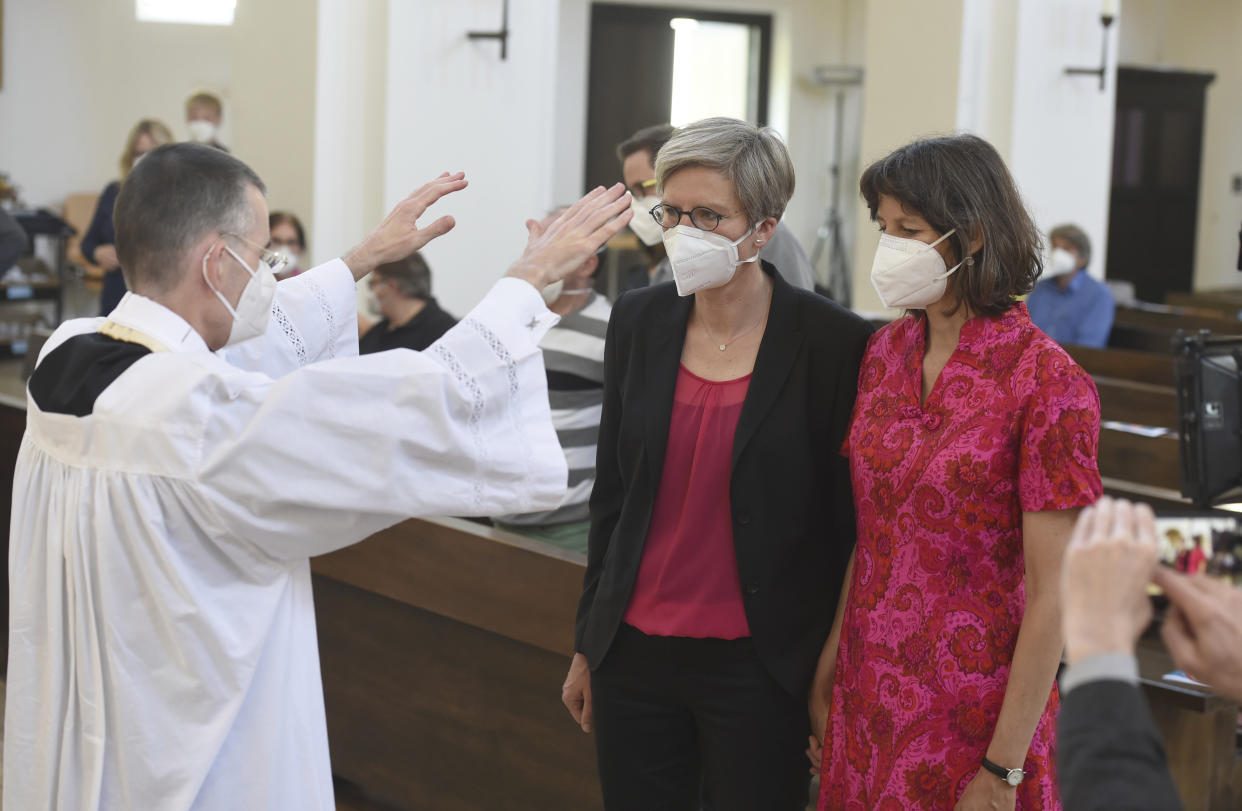 FILE - Vicar Wolfgang Rothe, left, blesses the couple Christine Walter, center, and Almut Muenster, right, during a Catholic service with the blessing of same-sex couples in St Benedict's Church in Munich, in this Sunday, May 9, 2021 file photo. In an interview with The Associated Press at The Vatican, Tuesday, Jan. 24, 2023, Pope Francis acknowledged that Catholic bishops in some parts of the world support laws that criminalize homosexuality or discriminate against the LGBTQ community, and he himself referred to homosexuality in terms of "sin." But he attributed attitudes to cultural backgrounds and said bishops in particular need to undergo a process of change to recognize the dignity of everyone. (Felix Hoerhager/dpa via AP, file)
