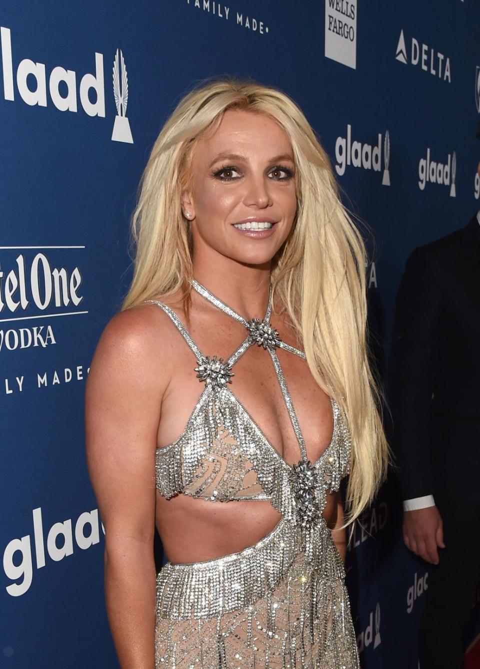 britney spears looking at the camera and posing on the carpet as she wears a silver beaded cutout dress