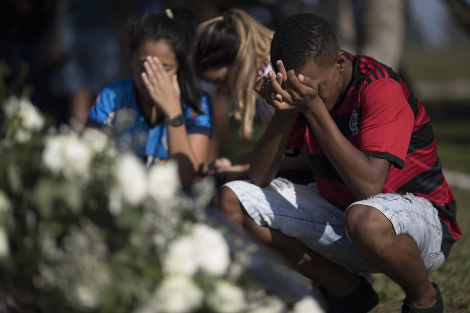 Friends grieve during the burial of the young soccer player Arthur Vinicius, one of the victims of a fire at a Brazilian soccer academy, in Volta Redonda, Brazil, Saturday, Feb. 9, 2019. A fire early Friday swept through the sleeping quarters of an academy for Brazil's popular professional soccer club Flamengo, killing several and injuring others, most likely teenage players, authorities said. (AP Photo/Leo Correa)