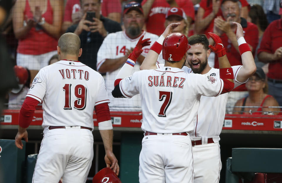 Cincinnati Reds' Eugenio Suarez (7) celebrates a two-run home run off Milwaukee Brewers starting pitcher Adrian Houser with Jesse Winker, rear, during the sixth inning of a baseball game, Monday, July 1, 2019, in Cincinnati. Reds' Joey Votto (19) scored on the play. Winker hit a solo home run earlier in the inning. (AP Photo/Gary Landers)