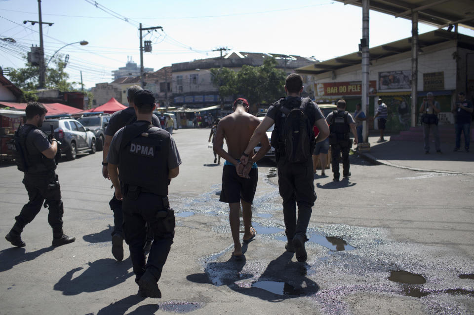 A suspect is detained during an operation at the Complexo de Alemao slum, in Rio de Janeiro, Brazil, Monday, Aug. 20, 2018. At least 11 people have been killed during shootouts involving military personnel and police in Rio on Monday. Since February, the military has been in charge of security in the state of Rio de Janeiro, which is struggling to curb a spike in violence. (AP Photo/Silvia Izquierdo)