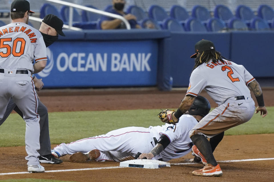 Miami Marlins' Sandy Leon slides safely into third base as Baltimore Orioles shortstop Freddy Galvis (2) is late with the tag, during the fifth inning of a baseball game, Wednesday, April 21, 2021, in Miami. (AP Photo/Marta Lavandier)