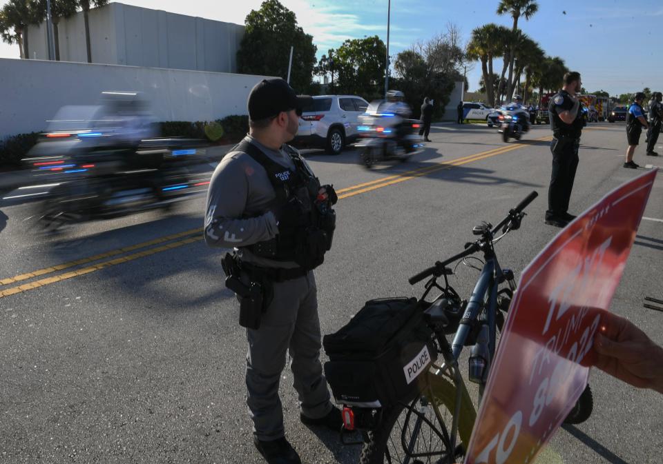 Offier Desilva, of the Jupiter Police department, watches the police motorcycles pass by Trump supporters as former President Donald Trump arrives at the Alto Lee Adams, Sr. United States Courthouse on Thursday, March 14, 2024, in Fort Pierce.