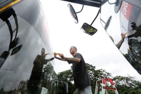 Workers paste stickers on new buses near Shwedagon Pagoda in Yangon, Myanmar July 21, 2017. REUTERS/Soe Zeya Tun