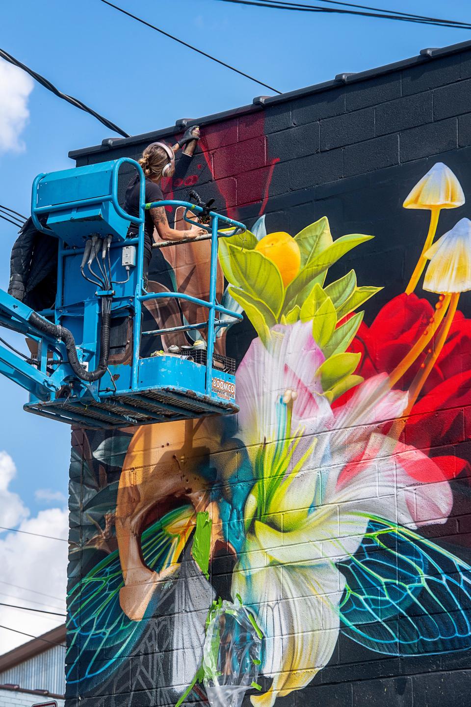 Artist Kathryn Crawford works on a mural on the side of Eulogy, Burial Beer Co.’s new music venue and bar, October 10, 2023.