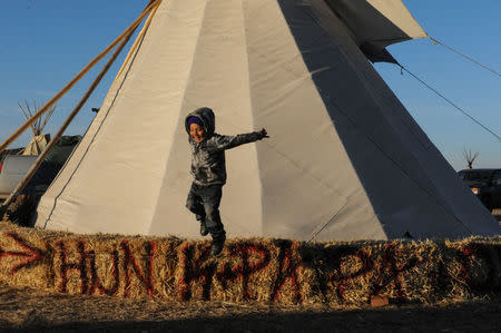 Kazlin Red Bear,4, from the Standing Rock Sioux tribe jumps from a hay bale in an encampment near the Standing Rock Indian Reservation. REUTERS/Stephanie Keith