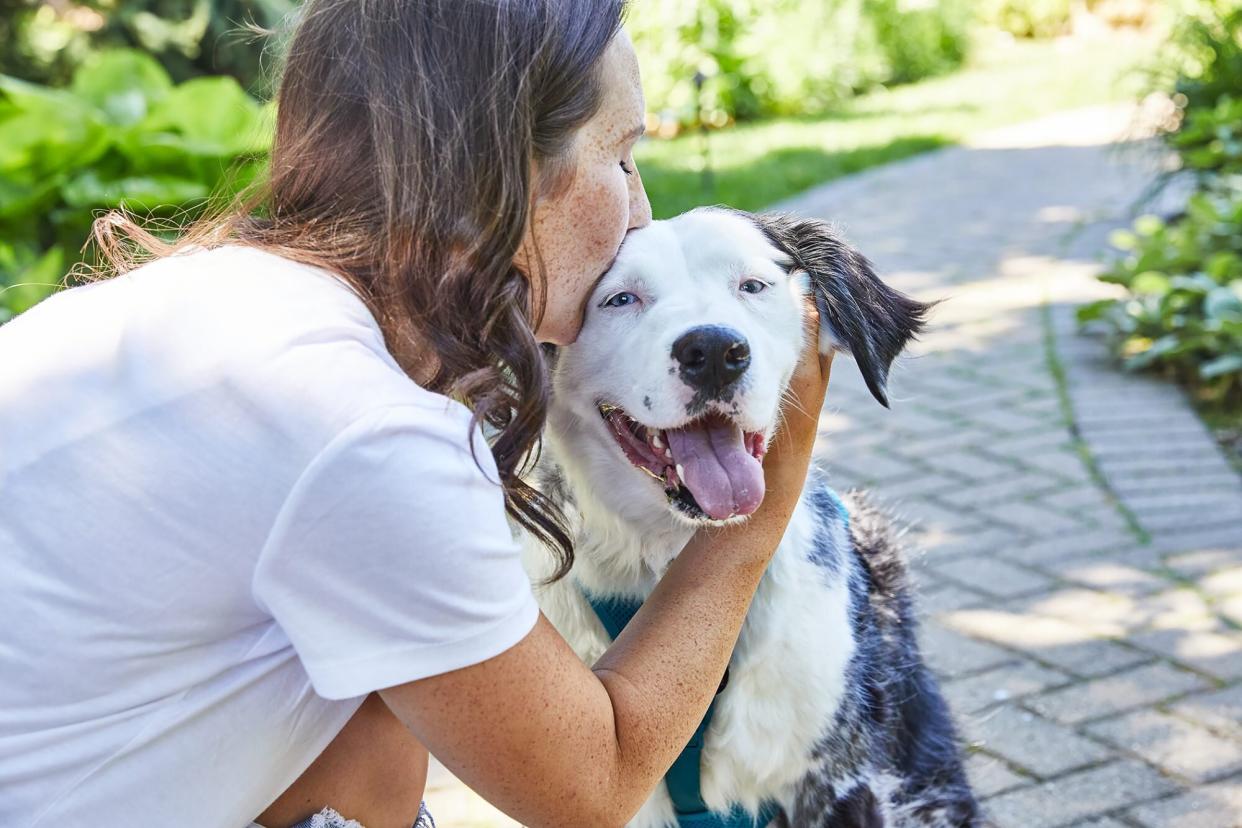 woman kissing dog; coping with pet cancer diagnosis