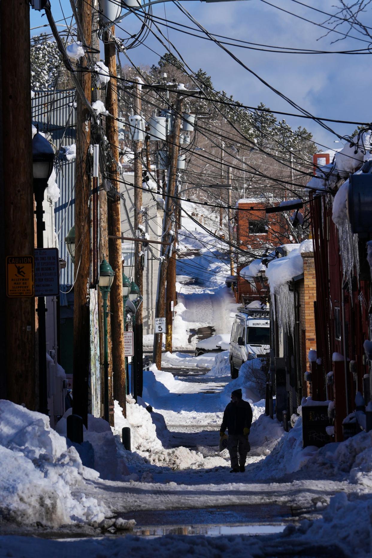 A man walks down an alleyway covered in snow in downtown on Jan. 18, 2023, in Flagstaff.