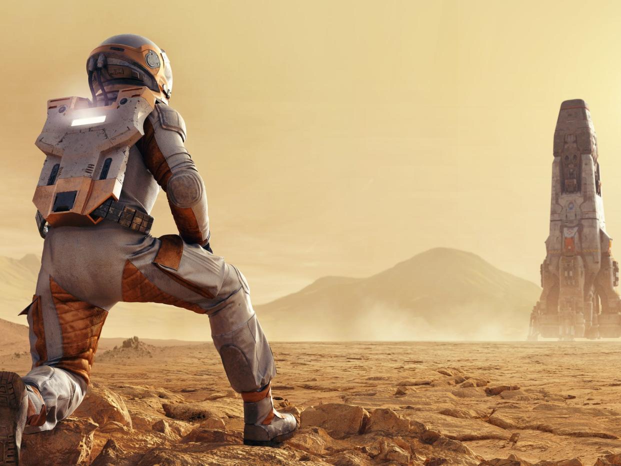 An artist's impression shows an astronaut kneeling down on Mars as a rocket is shown in the background. The landscape is barren and dusty.