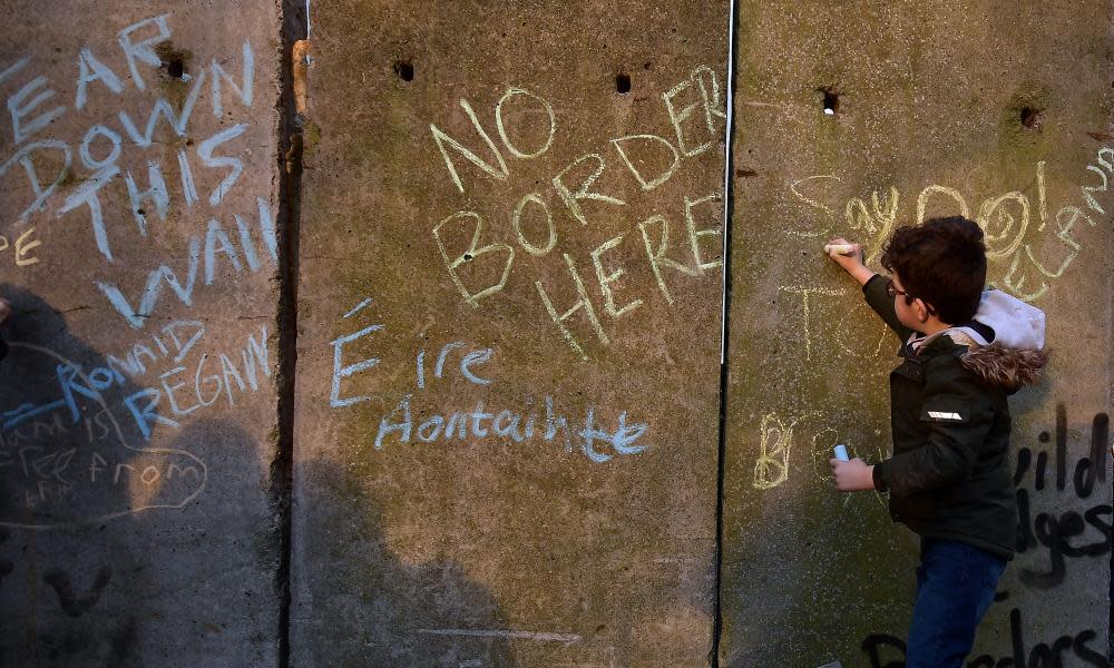 A young protester writes slogans on a mock border wall and customs checkpoint in Louth, Ireland, in January