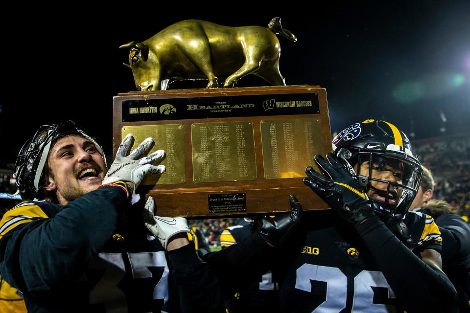 Iowa defensives back Riley Moss, left, and Kaevon Merriweather celebrate with the Heartland Trophy after a NCAA Big Ten Conference football game against Wisconsin, Saturday, Nov. 12, 2022, at Kinnick Stadium in Iowa City, Iowa. Iowa won, 24-10.