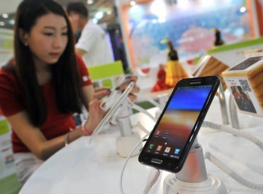 A South Korean woman inspects Samsung's smartphone 'Galaxy Note' during an IT show in Seoul, in May. A US appeals court gave Samsung a temporary reprieve on the sale of its Galaxy Nexus 7 smartphones while leaving intact a court ban on US sales of its tablet computers in a patent battle with Apple