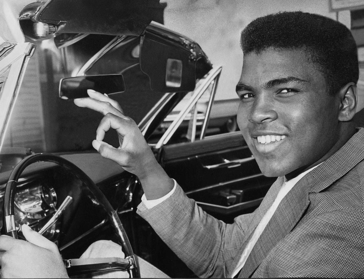 Ali gives a victory sign as he poses behind the wheel of his 1963 convertible after winning his driver?s license back on Mar 29, 1963.
Bud Kamenish/Courier Journal file
Cassius Clay a/k/a Muhammad Ali gave a victory sign as he posed behind the wheel of his 1963 convertible after winning his driver's license back. Mar 29, 1963