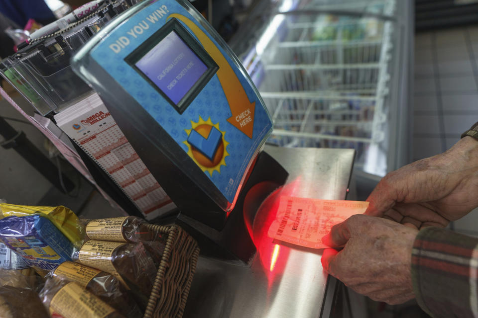 Roberto Ramirez checks his SuperLotto Plus ticket at a terminal at the gas station that previously sold the $2.04 billion-winning Powerball ticket award at Joe's Service Center, a Mobil gas station at Woodbury Road and Fair Oaks Avenue in Altadena, Calif., Friday, Jan. 6, 2023. Lottery players whose numbers didn't hit or who forgot to even buy a ticket will have another shot at a nearly $1 billion Mega Millions prize. The estimated $940 million jackpot up for grabs Friday night has been growing for more than two months and now ranks as the sixth-largest in U.S history. (AP Photo/Damian Dovarganes)