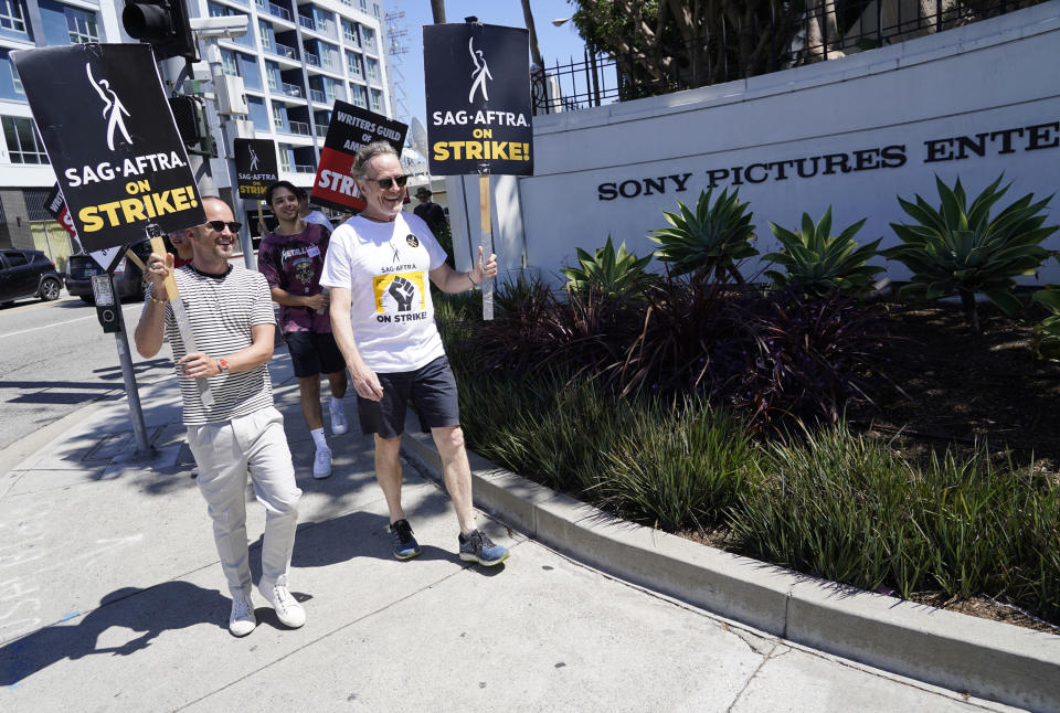 Aaron Paul, left, and Bryan Cranston, cast members from the television series "Breaking Bad," walk on a picket line outside Sony Pictures studios on Tuesday, Aug. 29, 2023, in Culver City, Calif. The film and television industries remain paralyzed by Hollywood's dual actors and screenwriters strikes. (AP Photo/Chris Pizzello)