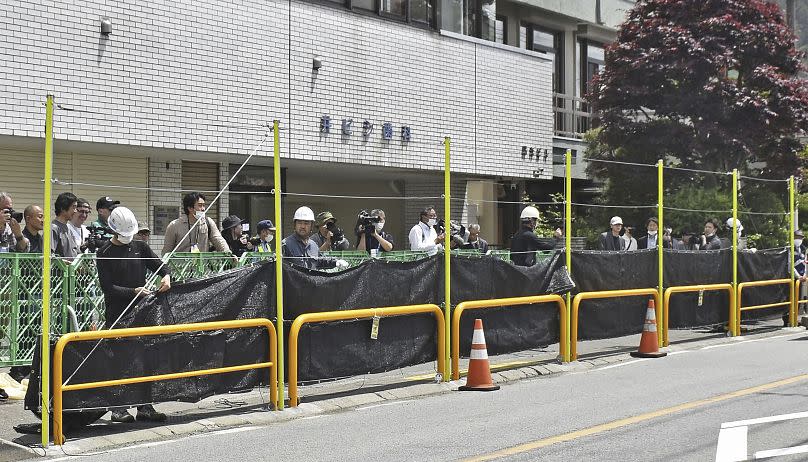 Workers set up a huge black screen on a stretch of sidewalk at Fujikawaguchiko town, Yamanashi prefecture, central Japan Tuesday, May 21, 2024.