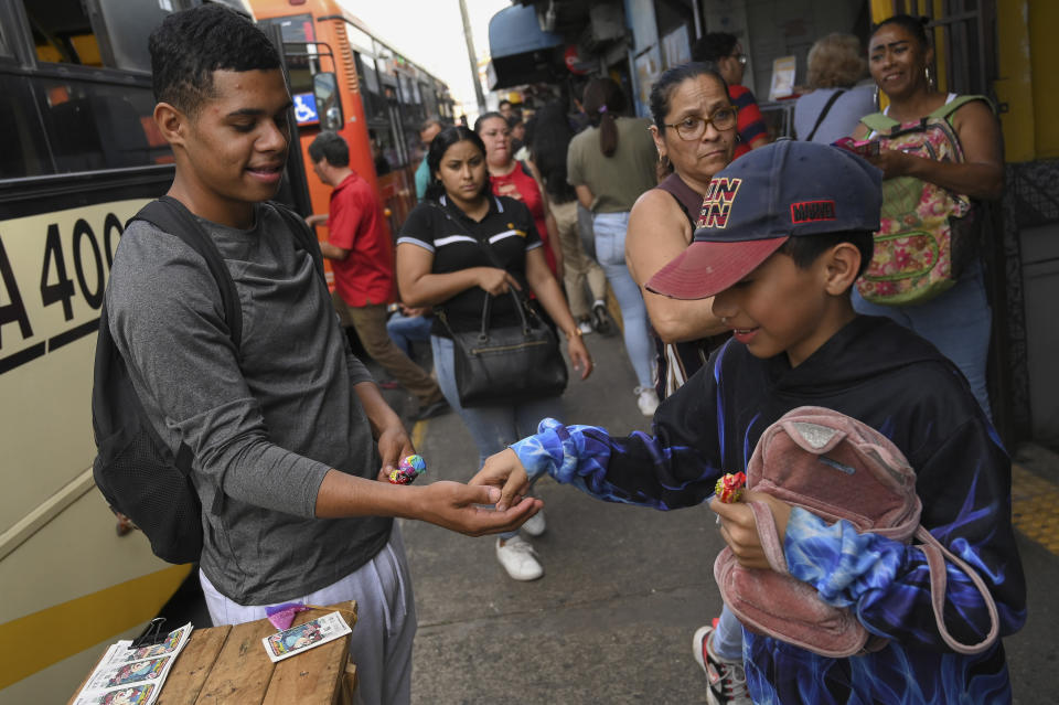 Venezuelan migrant Carlos Rivas, left, sells sweets on a street in Heredia, Costra Rica, Tuesday, Dec. 6, 2022. Faced with an overwhelmed asylum system, Costa Rica, one of the world’s great refuges for those fleeing persecution, is tightening its generous policies after President Rodrigo Chaves said the country’s system is being abused by economic migrants. (AP Photo/Carlos Gonzalez)