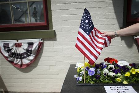 Gettysburg Museum of History curator Erik Dorr adjusts flags along the Memorial Day parade route, next to signs telling visitors not to ruin his flowers, before the event in Gettysburg, Pennsylvania, May 26, 2014. REUTERS/Mark Makela