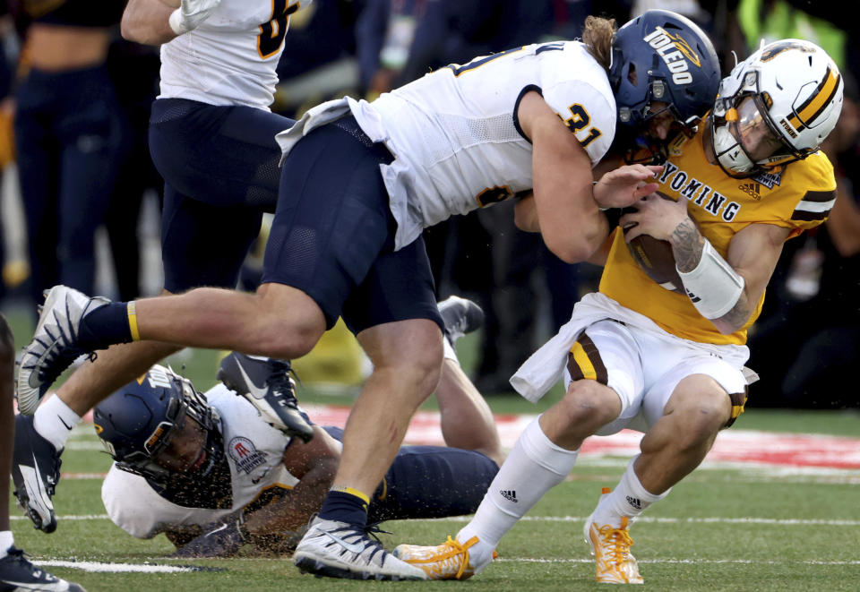 Toledo linebacker Daniel Bolden (31) takes down Wyoming quarterback Andrew Peasley (6) during the third quarter of the Arizona Bowl NCAA college football game Saturday, Dec. 30, 2023, in Tucson, Ariz. Bolden was ejected for targeting. (Kelly Presnell/Arizona Daily Star via AP)