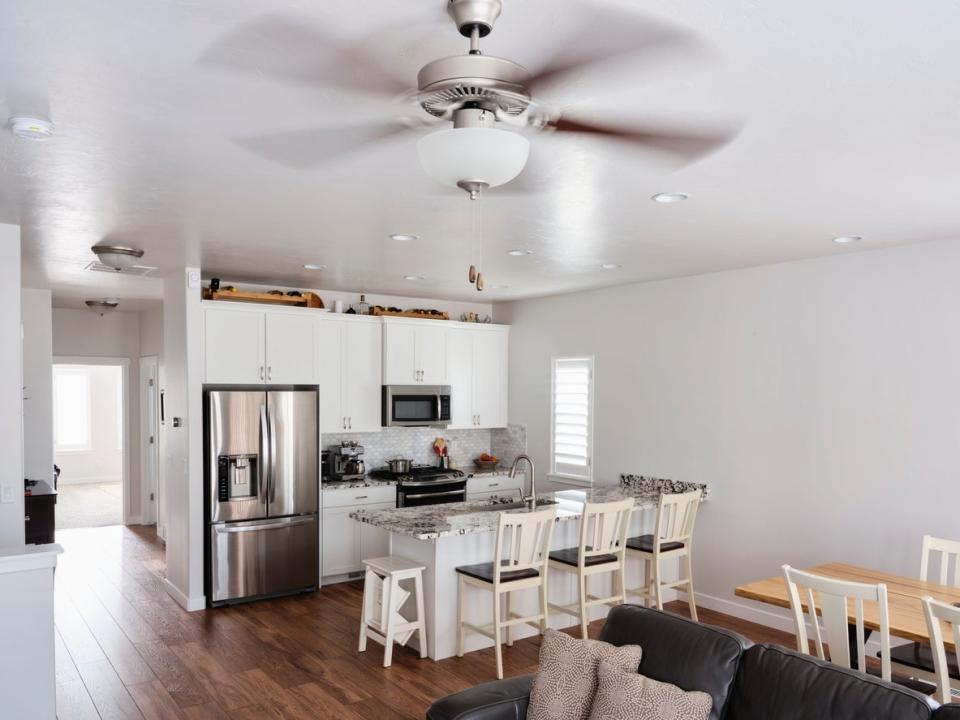 open plan living room and kitchen with ceiling fan spinning