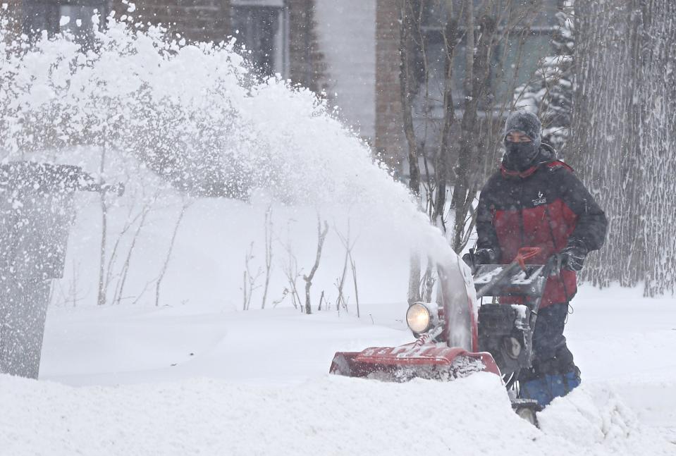 A man clears his driveway with a snow blower during a snowstorm in Quebec City