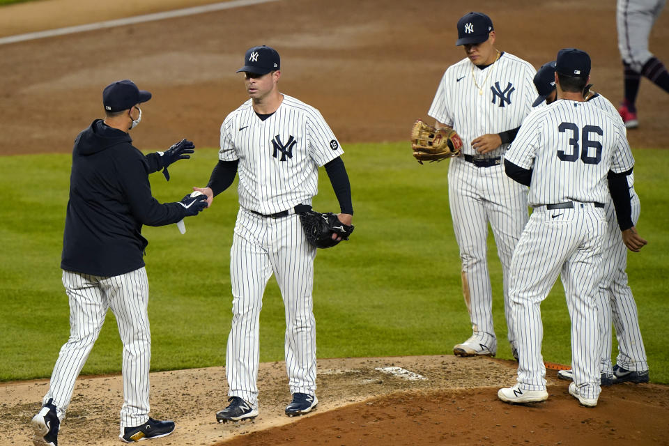 New York Yankees manager Aaron Boone. left, takes the ball from starting pitcher Corey Kluber as infielders stand on the mound during the fifth inning of the team's baseball game against the Atlanta Braves, Wednesday, April 21, 2021, at Yankee Stadium in New York. (AP Photo/Kathy Willens)