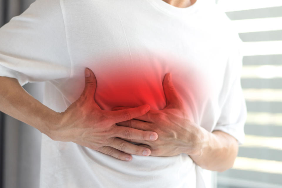 Man's hands on his chest in white shirt with red spot as suffering on chest pain. Male suffer from heart attack,Lung Problems,Myocarditis, heart burn,Pneumonia or lung abscess, pulmonary embolism day