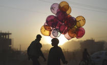 <p>Afghan boy Mahfouz Bahbah, 12, stands on a roadside hoping to sell his balloons during sunset in Kabul, Afghanistan, Oct. 18, 2011. (Photo: Muhammed Muheisen/AP) </p>