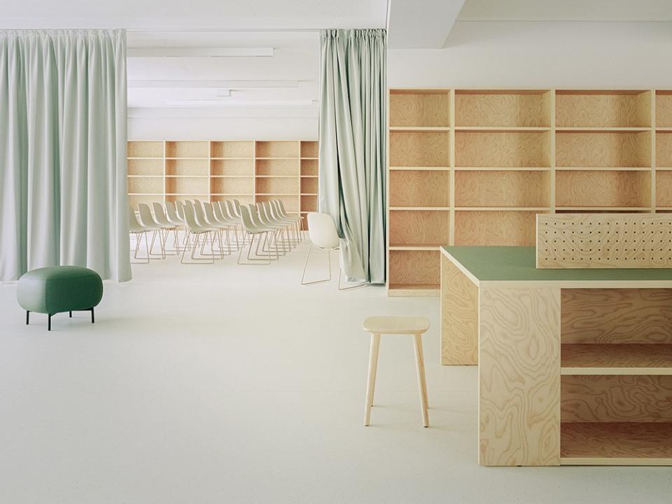 The simple white walls and floors contrast with the sea of unconventional green furniture and raw blond woods, making the school feel both modern and whimsical.
