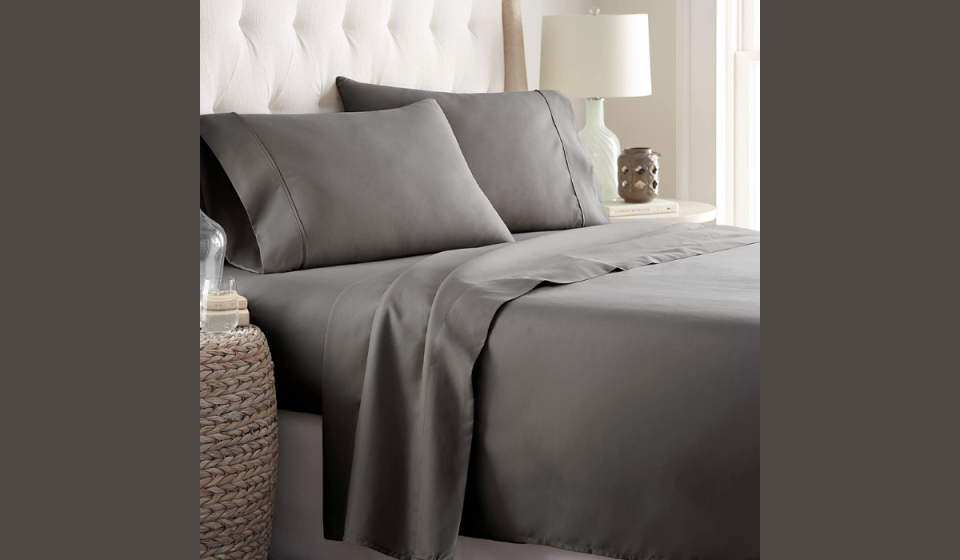 Grey sheets and pillows on a cozy looking bed with night tables on either side