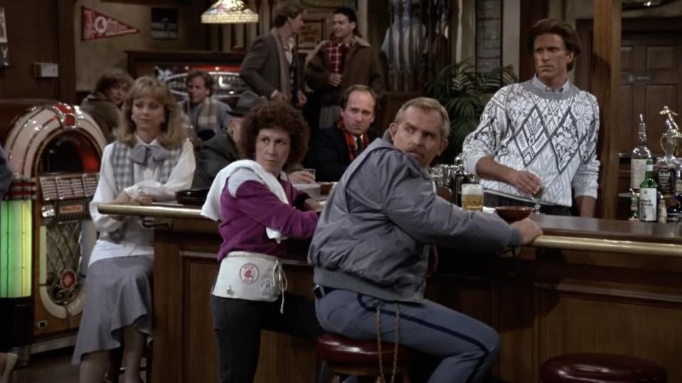 Main cast members from Cheers gathered around bar