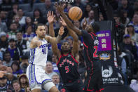 Sacramento Kings forward Trey Lyles (41) passes the ball past Toronto Raptors forward Precious Achiuwa (5)and Toronto Raptors forward Chris Boucher during the first quarter of an NBA basketball game in Sacramento, Calif., Wednesday, Jan. 25, 2023. (AP Photo/Randall Benton)