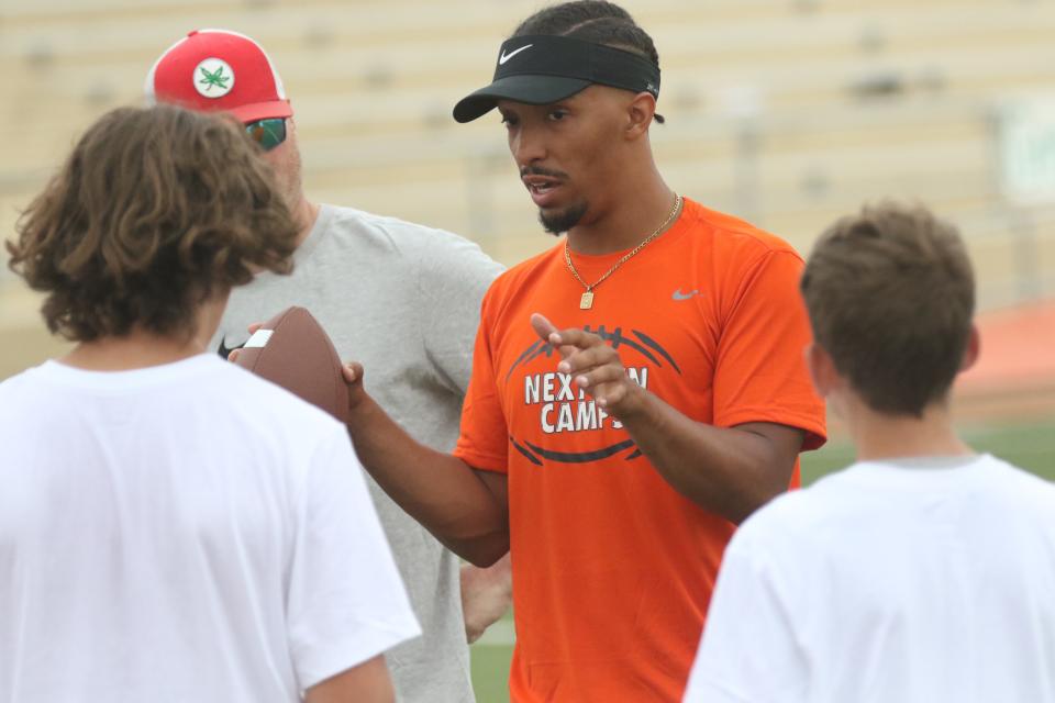 Former Mansfield Senior Tyger and current Ohio Dominican Panther Cam Todd talks with his group of quarterbacks during the 2022 Nike Skills Football Camp at Arlind Field this week.