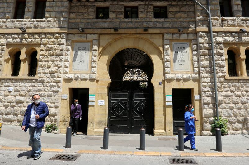 FILE PHOTO: People wearing masks walk near the main gate entrance of the American University of Beirut (AUB), in Beirut