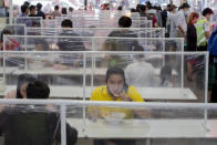 Customers eat in a food court at communal tables divided by plastic partitions in Bangkok, Thailand, Tuesday, May 19, 2020. Bangkok's beloved food hubs come alive as restrictions ease on food vendors. (AP Photo/ Gemunu Amarasinghe)