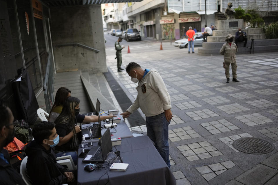 A man gives his fingerprint at a table set up by the National Election Council (CNE) where people can sign a petition in favor of holding a referendum to remove President Nicolas Maduro from office in Caracas, Venezuela, Wednesday, Jan. 26, 2022. The signatures of 20 percent of registered voter must be collected within 12 hours to request a presidential recall, a CNE rule that Maduro's opposition criticizes as impossible. (AP Photo/Matias Delacroix)