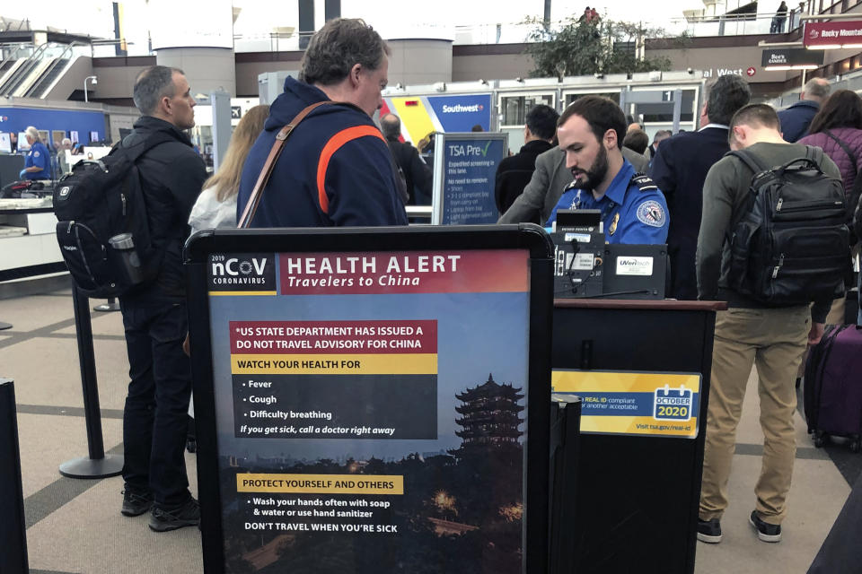 FILE - In this Monday, March 2, 2020 file photo, a health alert for people traveling to China is shown at a Transportation Security Administration security checkpoint at the Denver International Airport in Denver. President Donald Trump has repeatedly credited his February ban on travelers from mainland China as his signature move against the advance of the coronavirus pandemic -- a “strong wall” that allowed only U.S. citizens inside, he boasted in May. But Trump’s wall was more like a sieve. Exempted were thousands of residents of the Chinese territories of Hong Kong and Macau. (AP Photo/Charles Rex Arbogast, File)