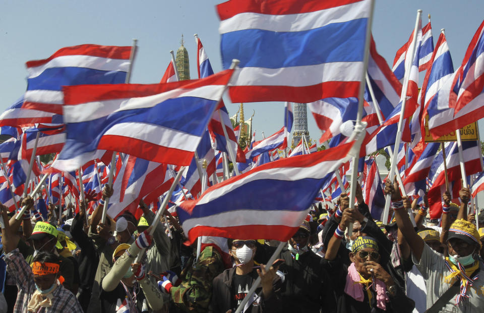 Anti-government protesters wave national flags during a rally in front of Grand Palace Wednesday, Jan. 15, 2014, in Bangkok, Thailand. Gunshots rang out in the heart of Thailand's capital overnight in an apparent attack on anti-government protesters early Wednesday that wounded at least two people and ratcheted up tensions in Thailand's deepening political crisis.(AP Photo/Sakchai Lalit)