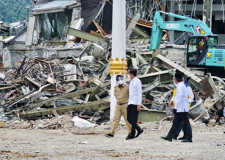 In this photo released by the Indonesian Presidential Palace, President Joko Widodo, center, talks to an official as he inspects an earthquake-damaged government building, in Mamuju, West Sulawesi, Indonesia, Tuesday, Jan. 19, 2021. Widodo visited the areas where a deadly earthquake left thousands of people homeless in an effort to reassure them the government's response is reaching those struggling after the quake. (Indonesian Presidential Palace via AP)