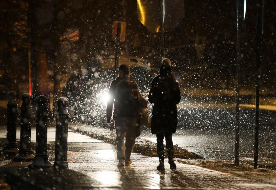 People walk along N. Franklin Street in the Cool Spring neighborhood as snow falls in Wilmington early Friday evening, Jan. 28, 2022.